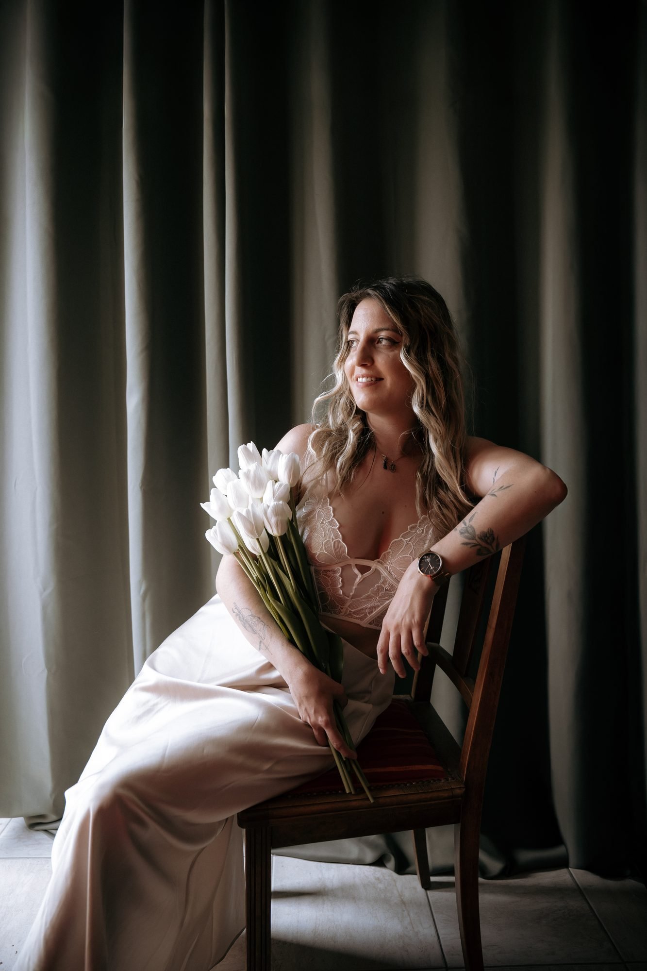 Portrait d'une femme assise, tenant un bouquet de tulipes blanches, lumière tamisée