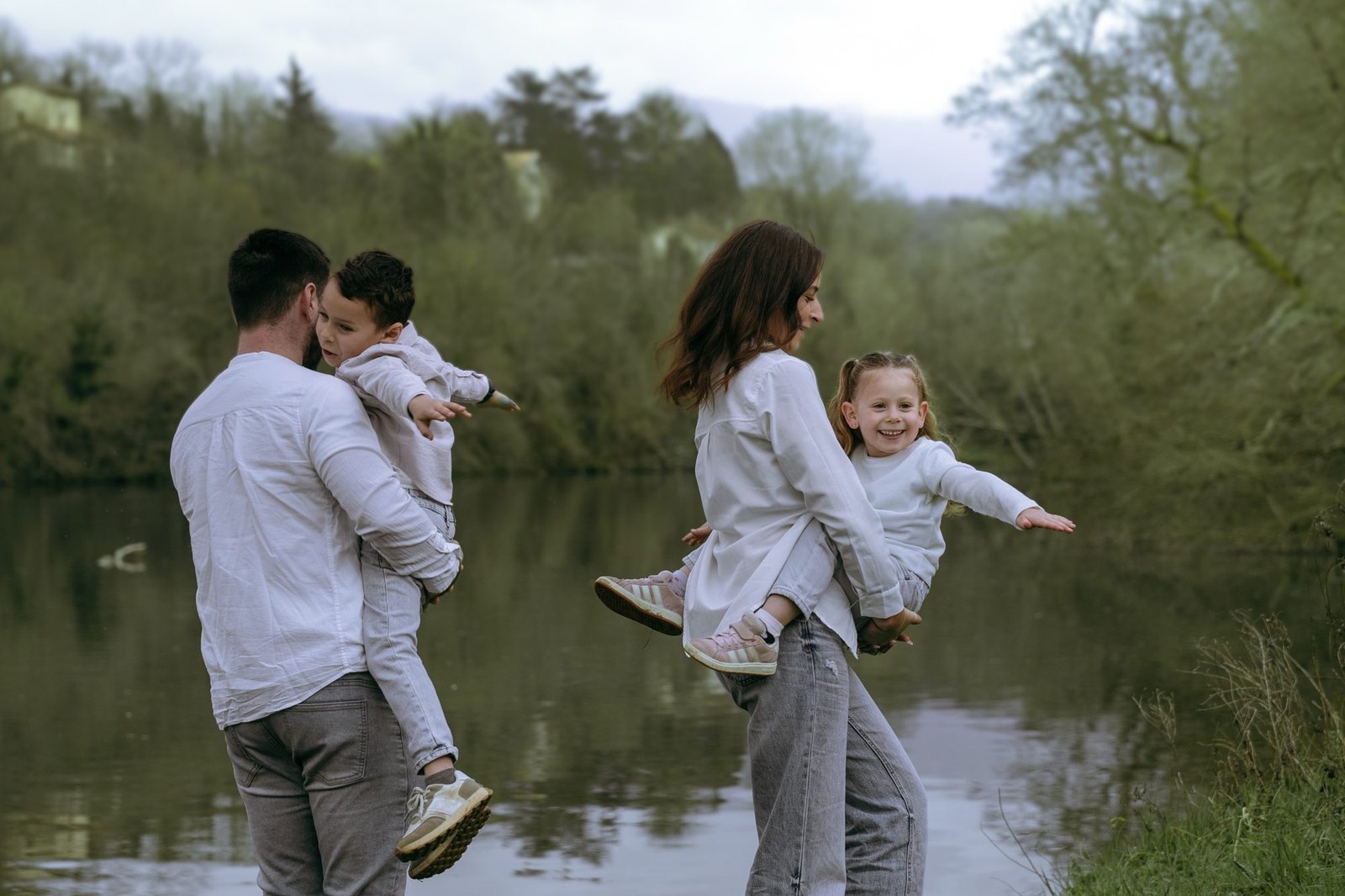 Famille au bord d'un étang, les enfants soulevés dans les bras de leurs parents