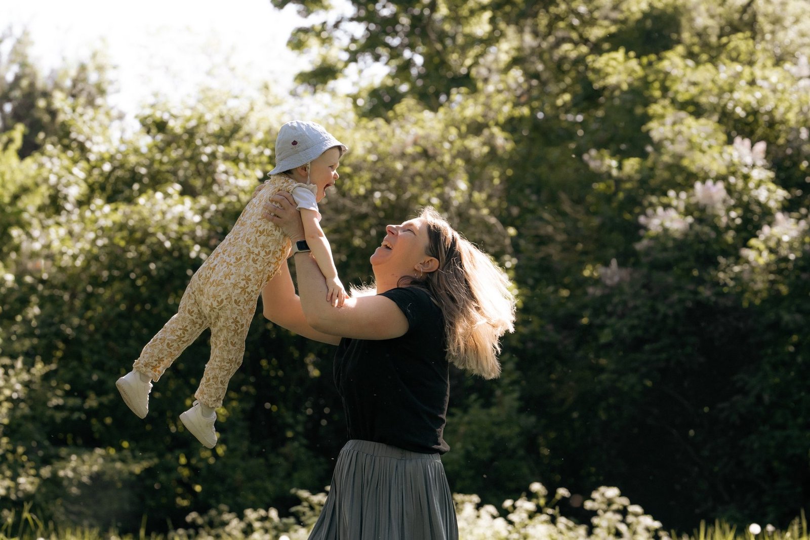 Bébé blotti dans les bras de sa maman, lumière douce à la fenêtre
