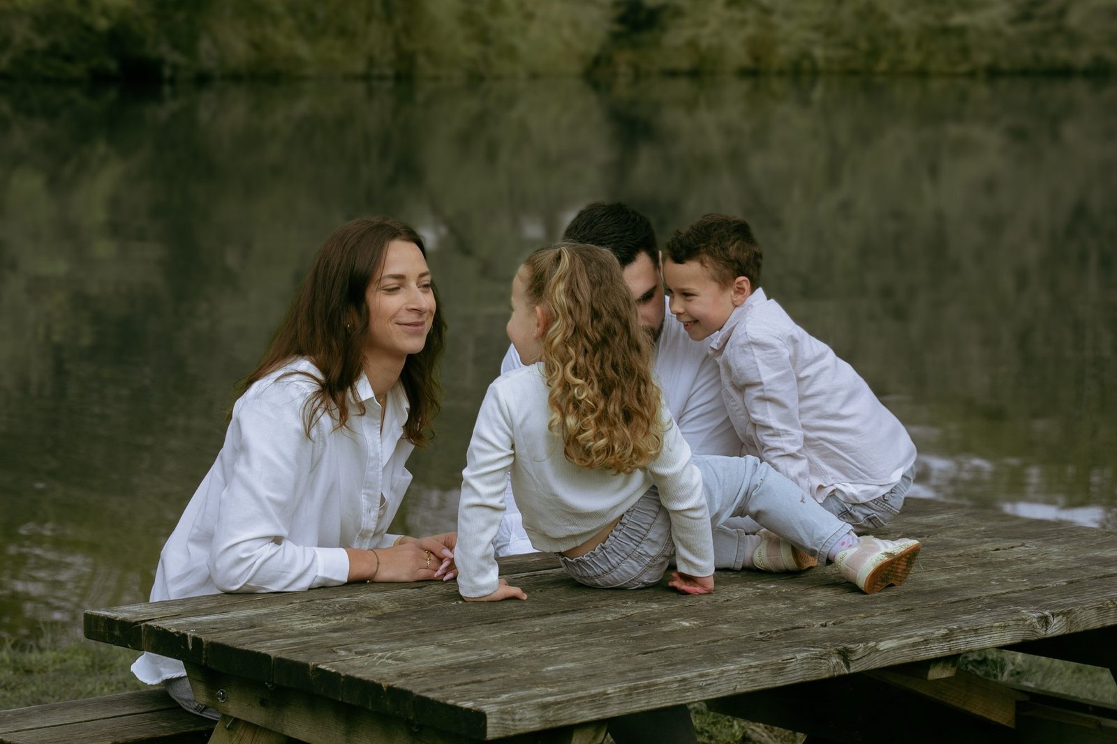 Famille réunie sur une table en bois au bord de l'eau, moment complice
