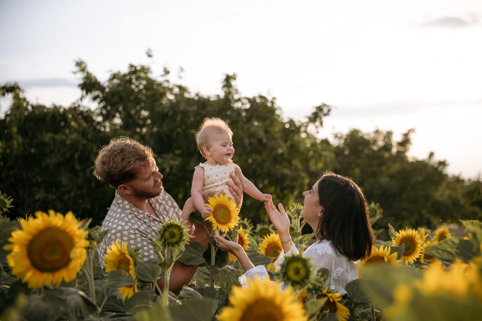 Maman embrasse son bébé entourée de tournesols