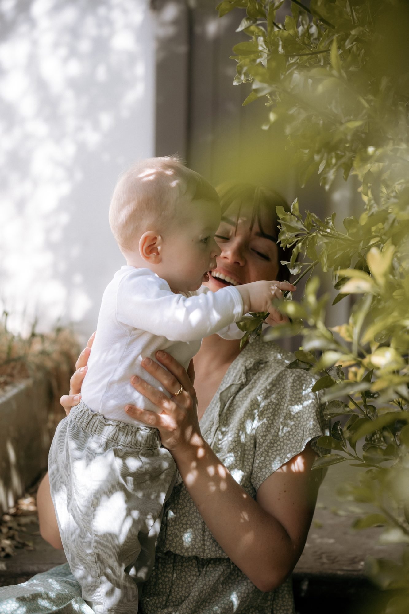 Bébé cueillant des fleurs dans les bras de sa maman, jardin ensoleillé