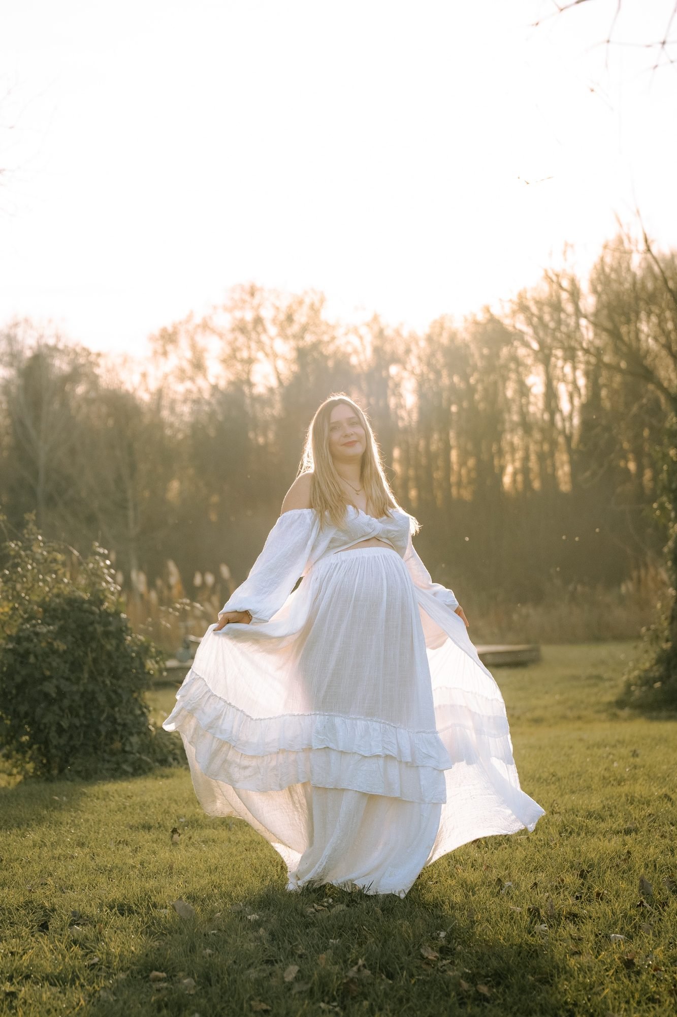Femme enceinte devant une fenêtre, robe satinée