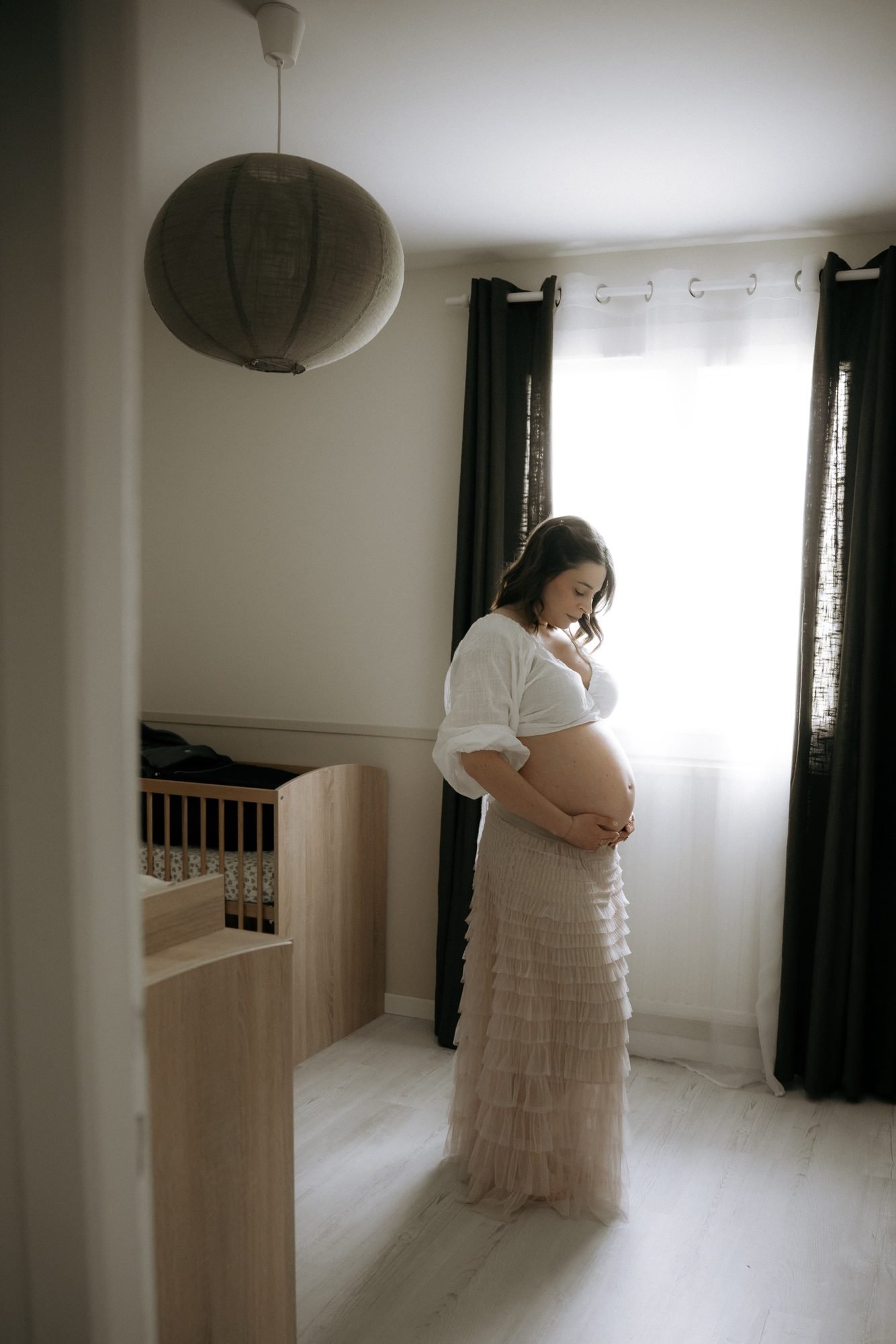 Femme enceinte devant une fenêtre ouverte sur le jardin