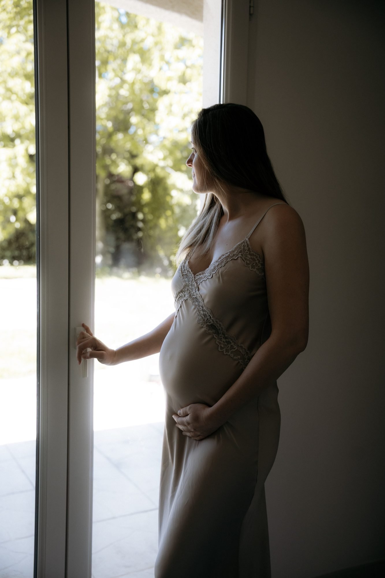 Femme enceinte de profil devant une cascade, tenant son ventre