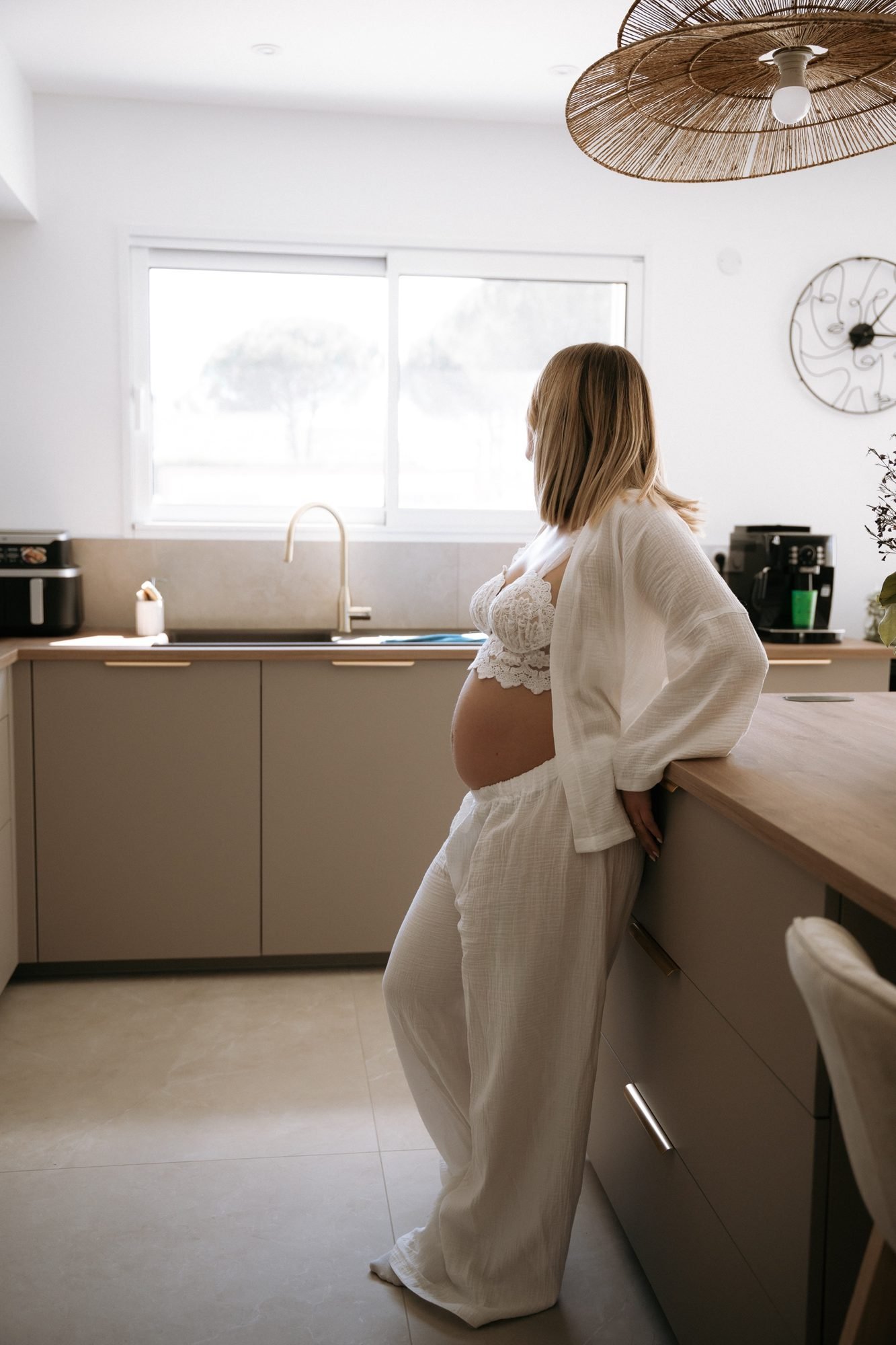 Femme enceinte de profil devant une cascade, main dans les cheveux