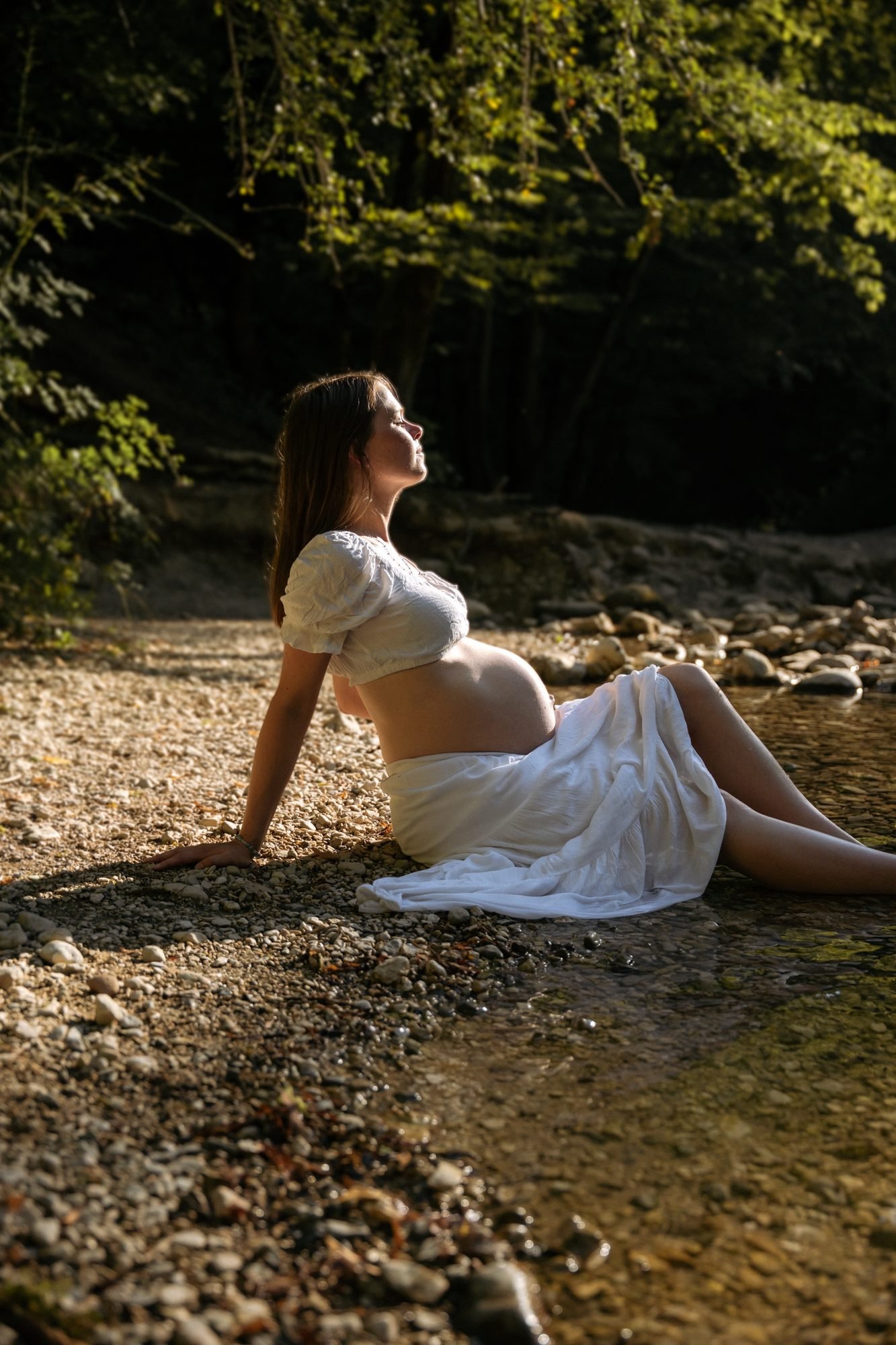 Mère et fille câlines au bord d'une rivière, femme enceinte