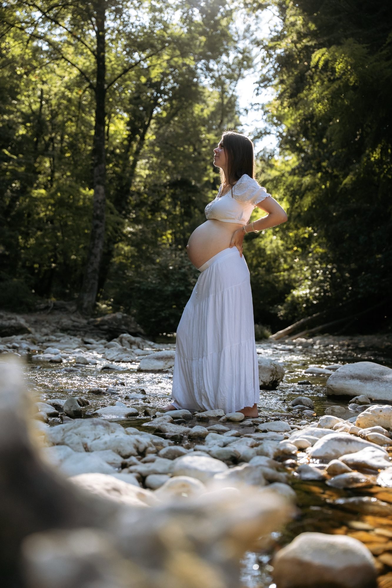 Femme enceinte souriante dans un champ, lumière naturelle