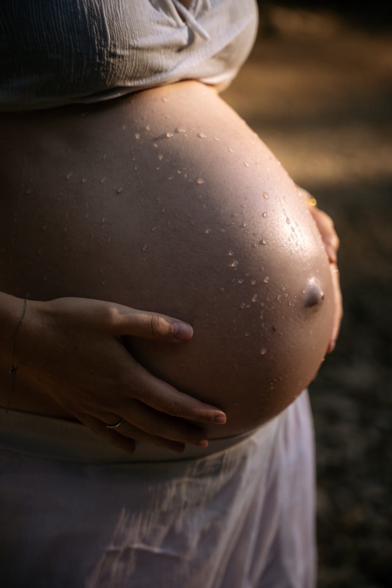 Femme enceinte tenant son ventre, regard vers le bas