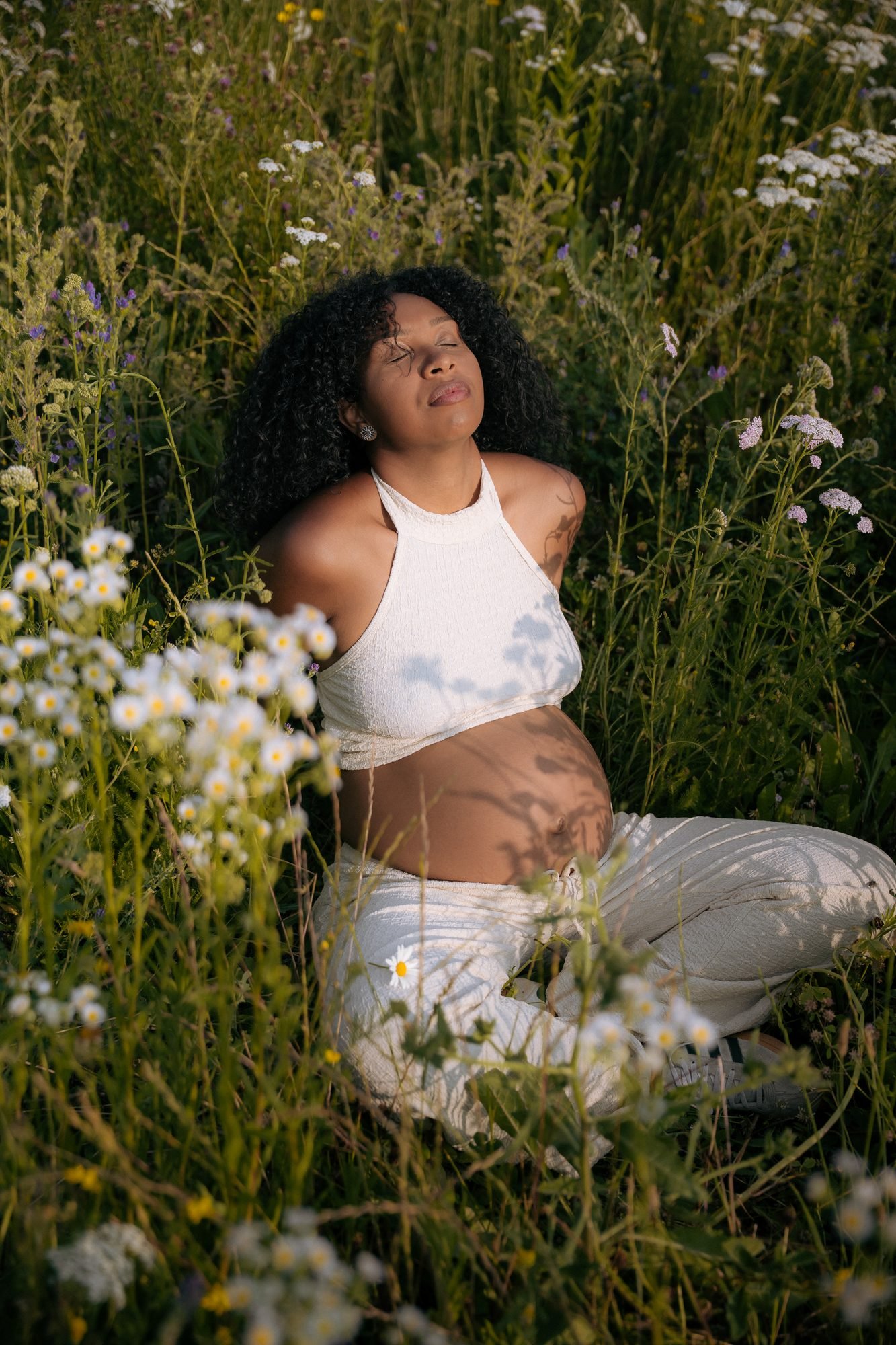 Femme enceinte allongée dans un champ de fleurs sauvages, yeux fermés