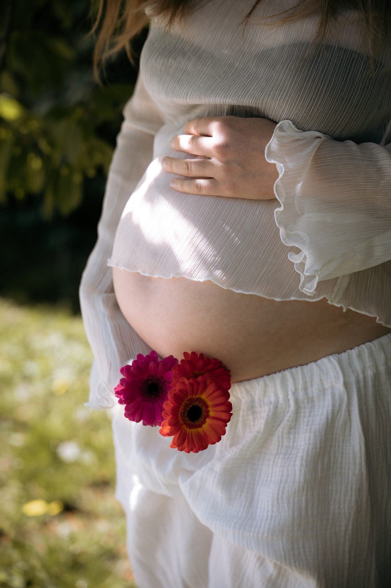 Ventre de femme enceinte orné de fleurs roses et oranges