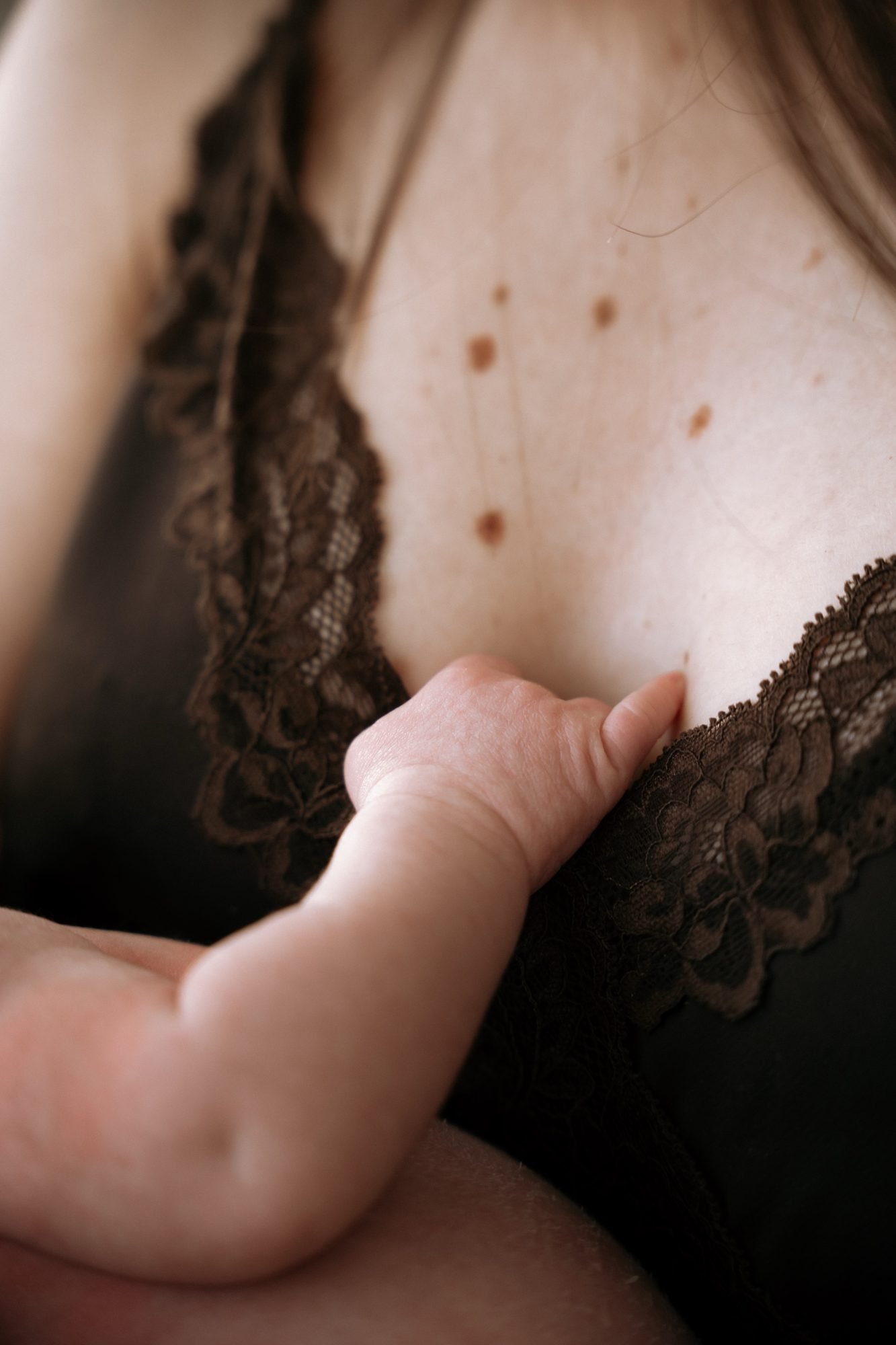 Gros plan sur la main d'un nouveau-né posée sur la peau de sa mère, dentelle noire