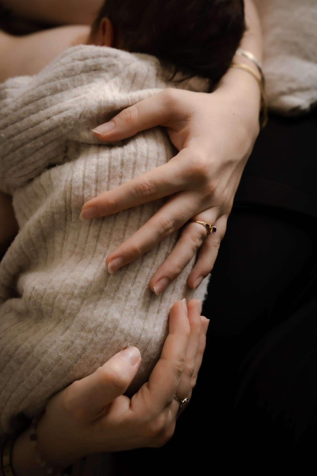 Mains posées sur un ventre, bague dorée, gros plan