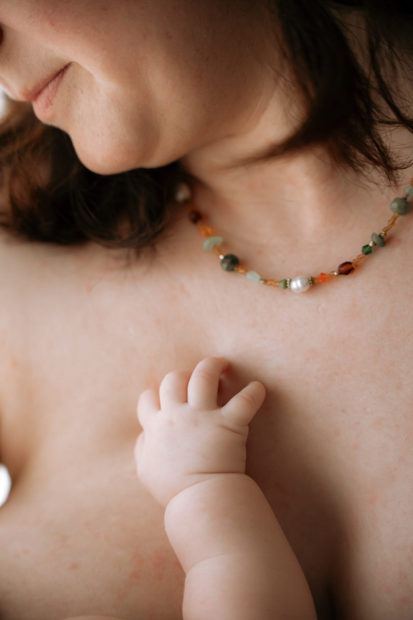 Gros plan sur la main d'un nouveau-né posée sur le collier de sa mère