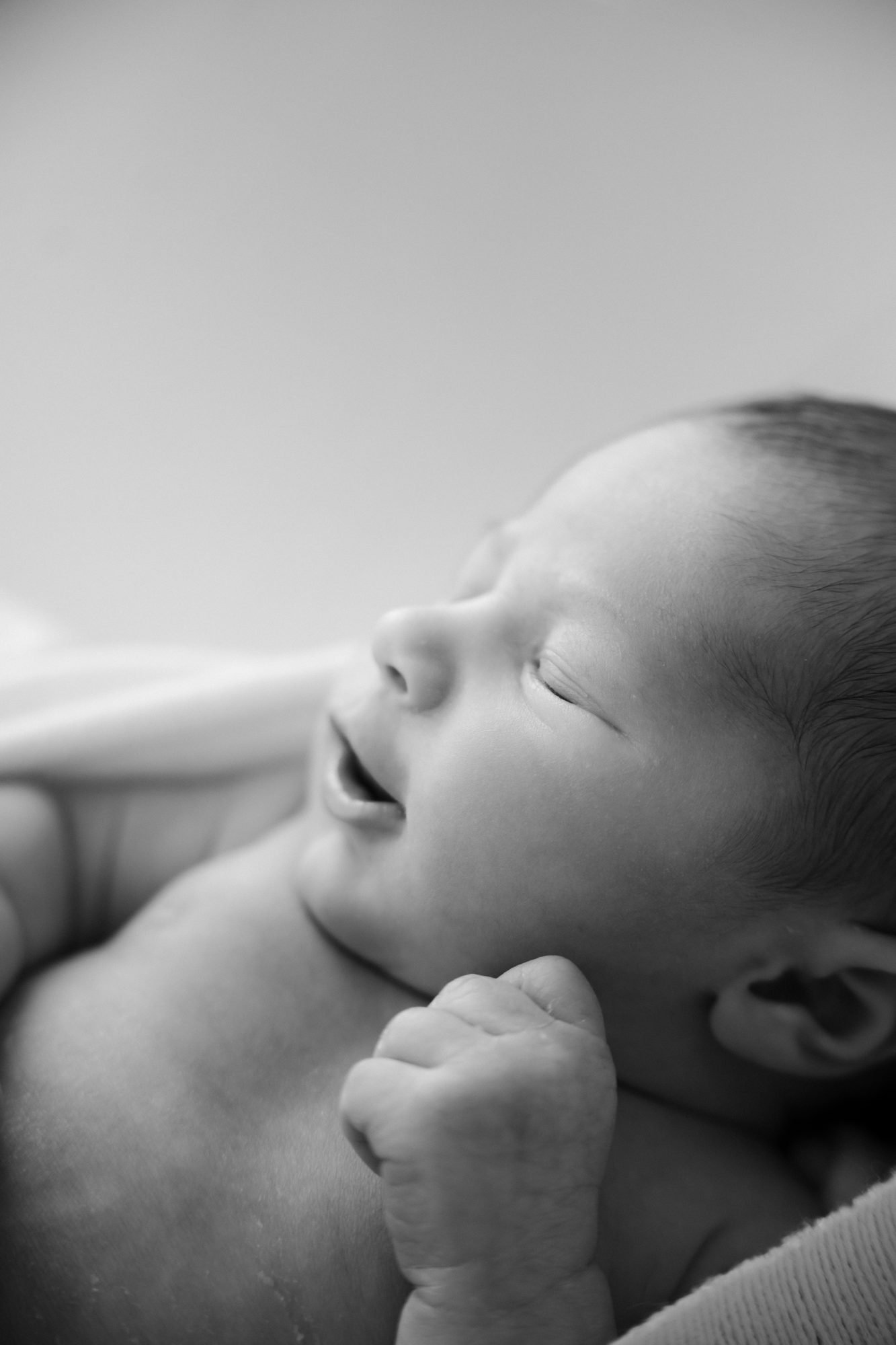 Gros plan en noir et blanc sur le visage endormi d'un nouveau-né qui bâille