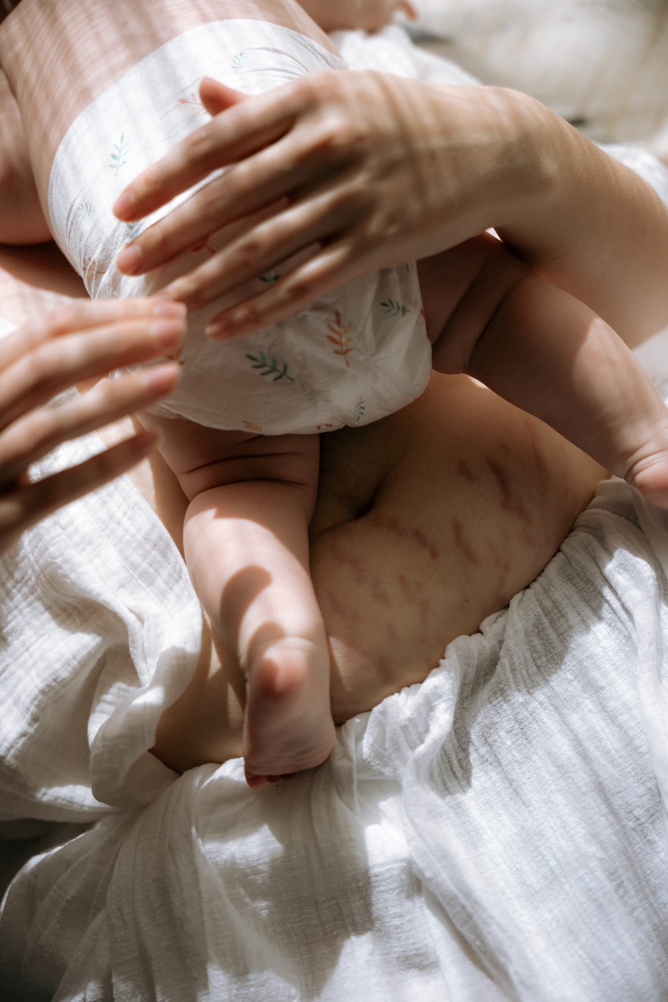 Mains d'une mère autour de son bébé, moment tendre du change