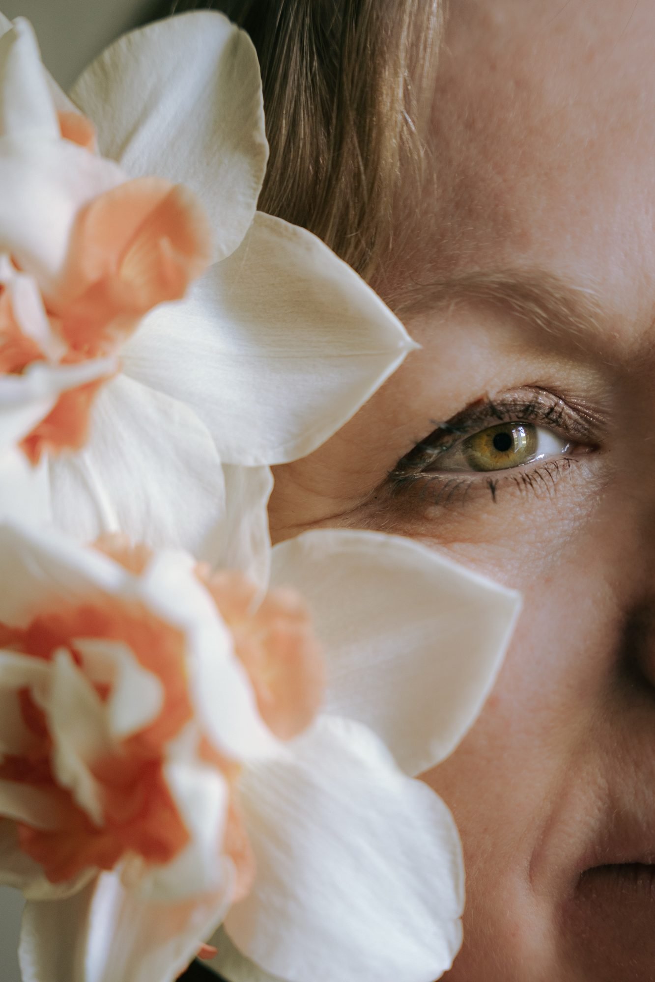 Gros plan sur le regard, entouré de fleurs pêche et blanches