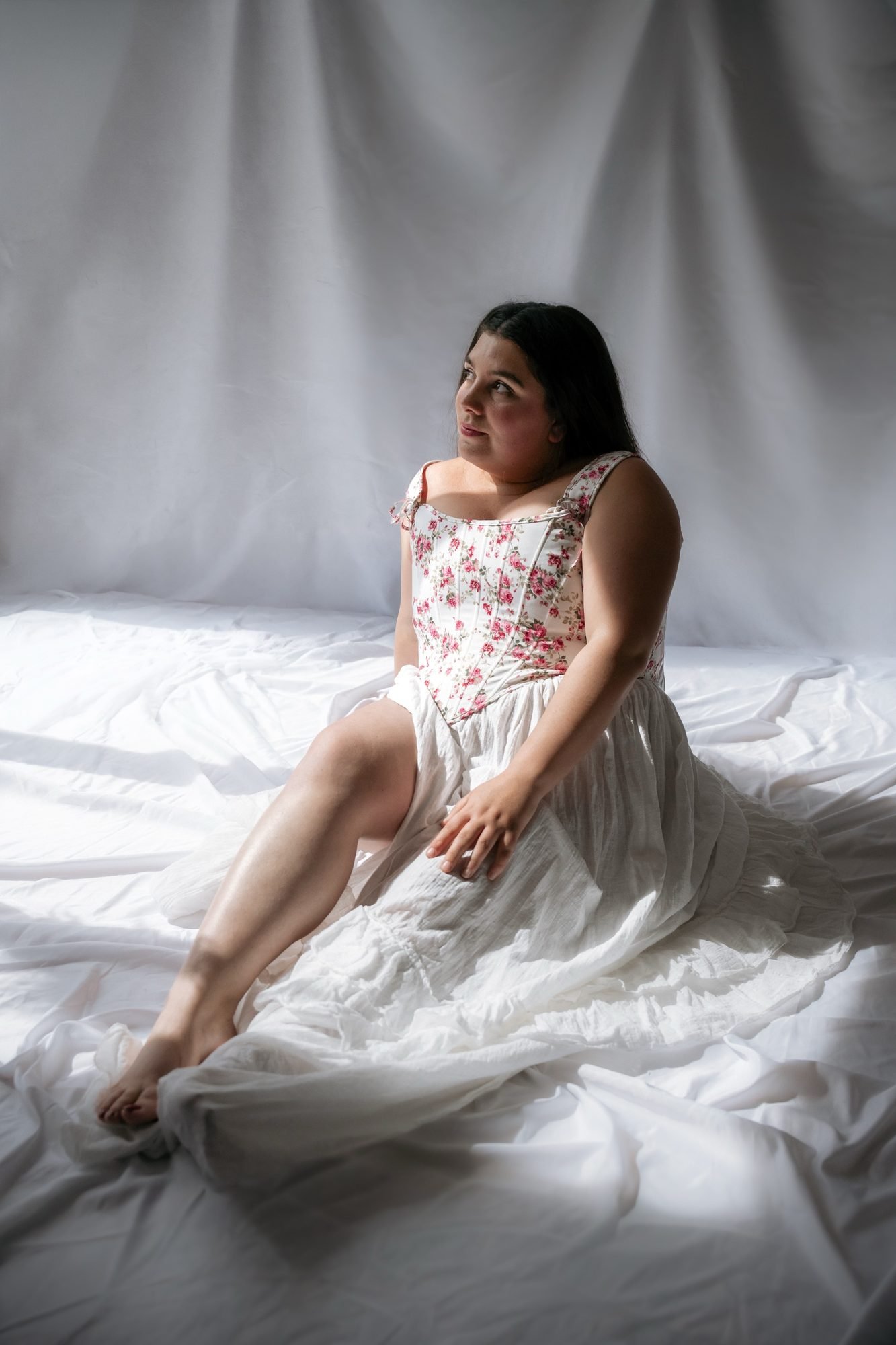 Assise dans la lumière, robe fleurie et regard vers le ciel