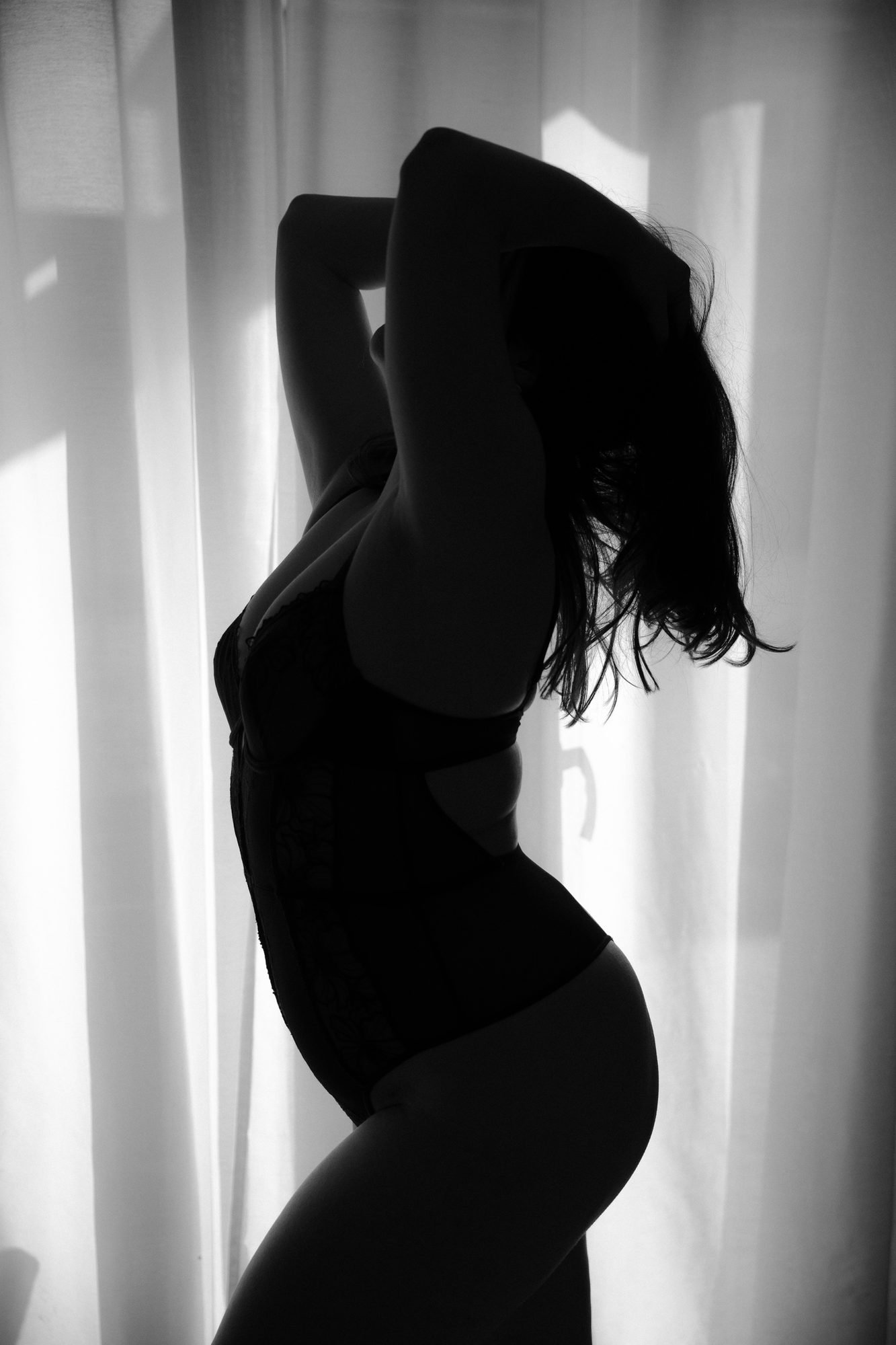 Silhouette à contre-jour devant le rideau, bras levés