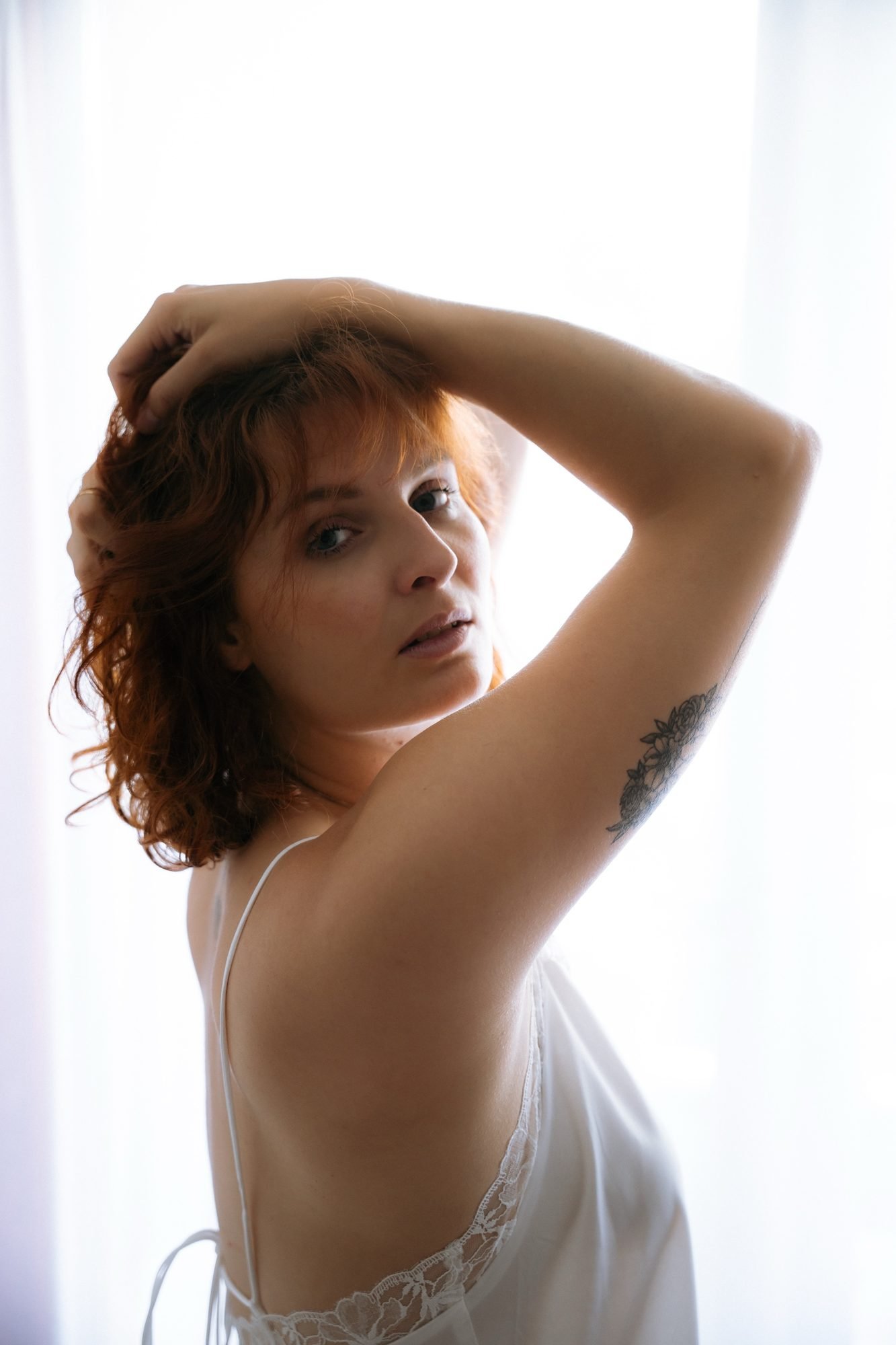 Portrait direct, bras levé et tatouage floral à l'épaule