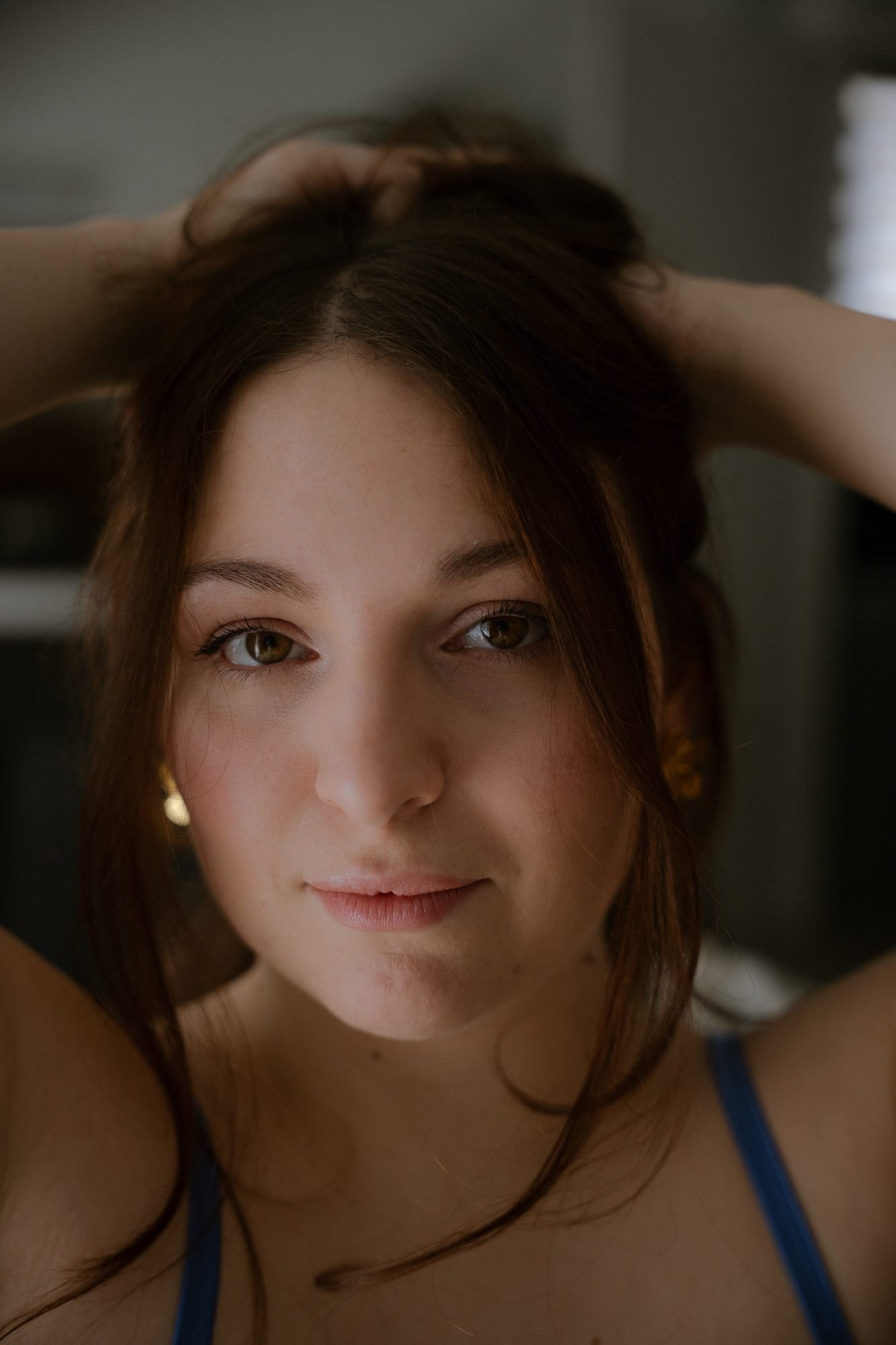 Portrait rapproché, mains dans les cheveux, regard direct vers l'objectif